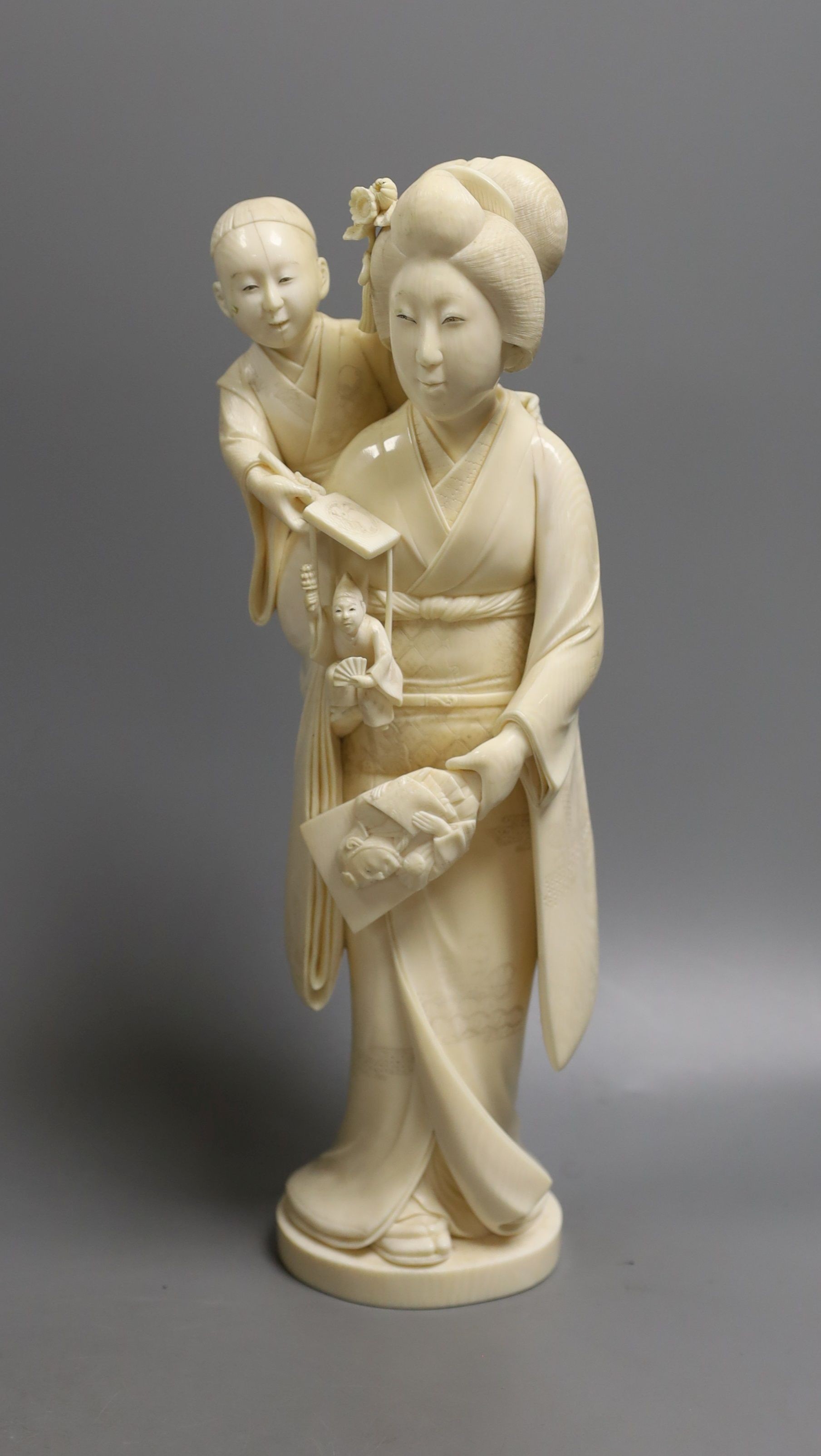 A large Japanese Tokyo School ivory okimono of a lady with child holding a puppet, Meiji period, 31 cms high.